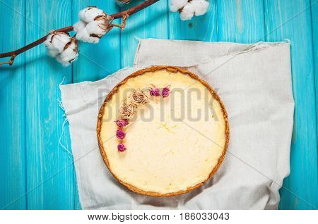 Homemade cheesecake - healthy organic summer dessert pie cheesecake. Cheese cake on blue wood table. Decoration of dried flowers. Top view