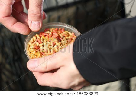 Angler holds a box of worms in his hand