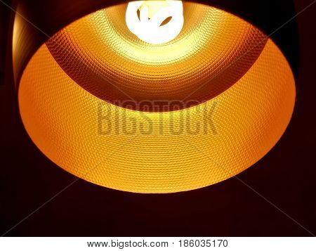 Closed up of black orange ceiling lamp with energy saving fluorescent light bulb