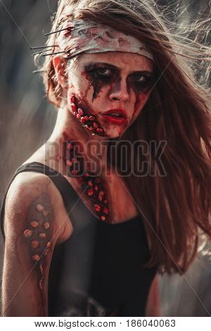 Mutant girl portrait in wounds and ulcers with nails in her head. On her head is bandage.