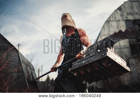 Mutant monster with weapon in form of hammer saw and an ax. Imagination. Mutant with sack on his head.