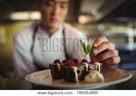 Close-up of male chef garnishing dessert plate in commercial kitchen