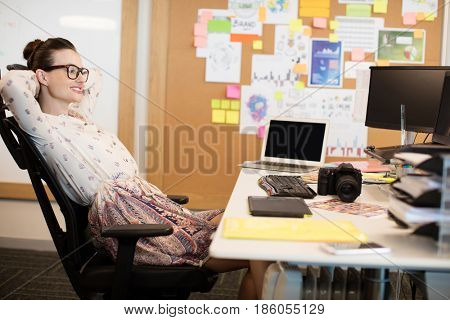 Smiling designer relaxaing on chair at creative office