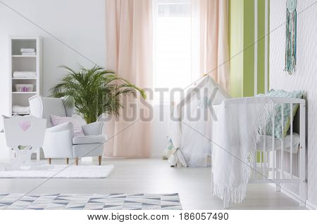 White modest interior of baby room with cradle
