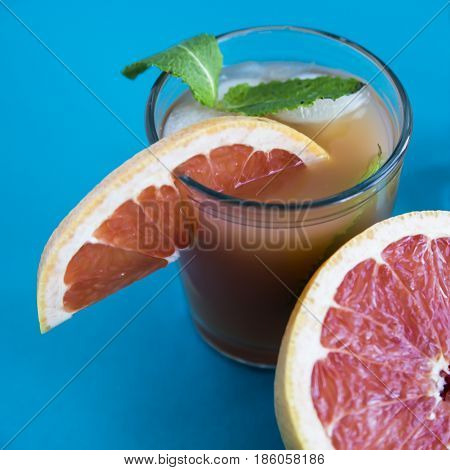 Grapefruit alcoholic cocktail with pieces of fruit, ice and mint