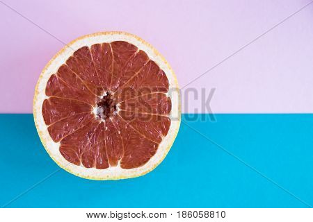Cut in half a grapefruit on a pink and blue background