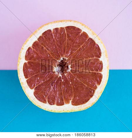 Cut in half a grapefruit on a pink and blue background