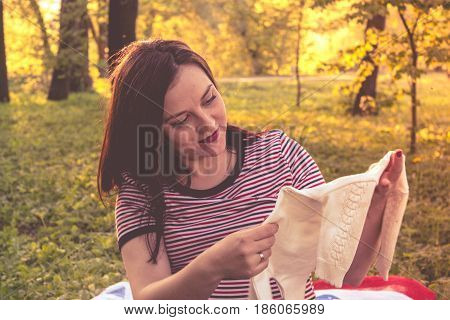 Happy young pregnant woman playing with baby sweater. slowmotion