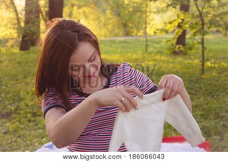 Happy young pregnant woman playing with baby sweater. slowmotion
