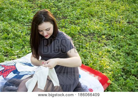 Happy young pregnant woman playing with baby sweater. slowmotion