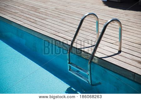 water sport and summer holidays concept - outdoor swimming pool ladder