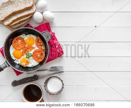 Eggs cooked overeasy with fried tomatoes and parsley, homemade bread, additional text space left, topview