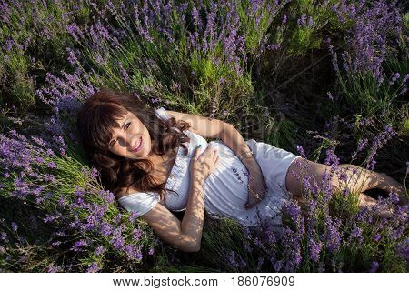 pregnant woman lies in a field of flowers of lavender