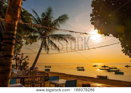 Beautiful Beach With A Cafe In Sanur With Local Traditional Boats Palm Trees On The Island Of Bali A