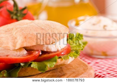 Puccia bread with mozzarella and tomato on cuttingboard.