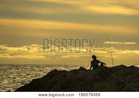 Silhouette of people enjoying the Surf fishing with background of beautiful sunset.Surf fishing is the sport of catching fish standing on the shoreline or wading in the surf.