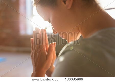 religion, faith and people concept - close up of woman meditating at yoga studio