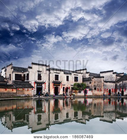 HONGCUN, CHINA - APRIL 20, 2014: Tourist walking around Moon Lake in ancient Hongcun Village