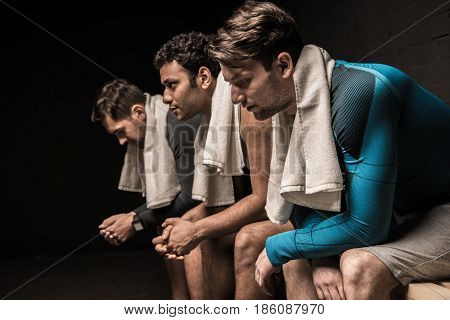 Tired Male Athletes Resting At Gym Locker Room