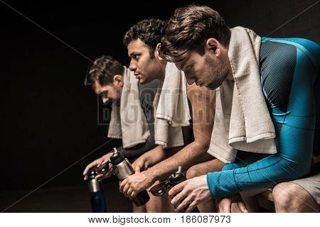 Tired Male Athletes Resting At Gym Locker Room