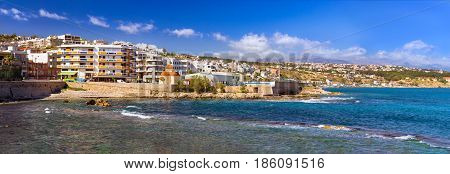 Classic and modern Greek architecture on coast of Kolpos Almirou in resort Rethymno. Promenade Leof. Emmanouil Kefalogianni is washed by Cretan sea. Church of Holy Chapel Of Saint Nicholas. Greece