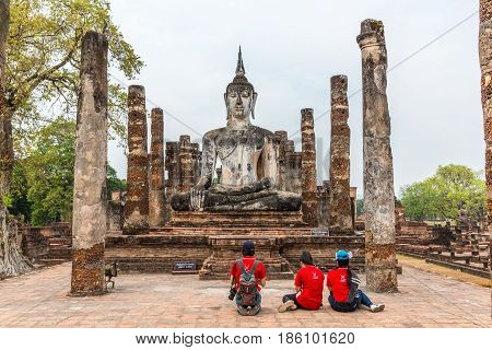 SUKHOTHAI THAILAND - APRIL 1 2016: Three people with red T-shirts worshipping Buddha Image in Sukhothai historical park Sukhothai.