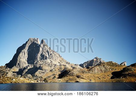 Midi Dossau Peak reflected in Gentau lake. Ossau Valley, Pyrenees National Park, Pyrenees, France.