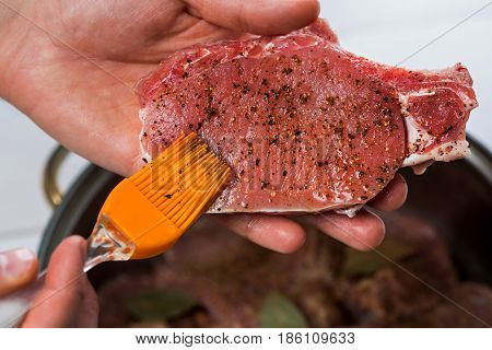 Close up of chefs hands spicing the meat. Casserole with raw meat on a white background.