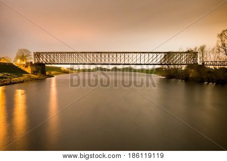 Old industrial railway railroad iron bridge center perspective over river in night