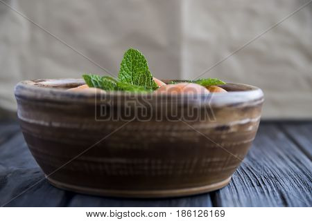 Ripe orange apricots in a clay bowl on a wooden table