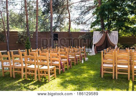 Beautiful Wedding Ceremony Outdoors. Decorated Chairs Stand On The Grass. Wedding Arch Made  Flowers