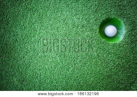 Mini golf scene with ball and hole. Can be used like background. Sunny day at resort park