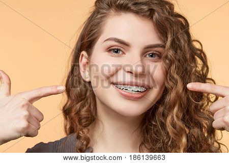 curly hair woman with brackets on biege background