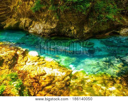 Pure blue water of Radovna river in Vintgar Gorge. Natural waterfalls, pools and rapids and tourist wooden path. Slovenia, Europe.