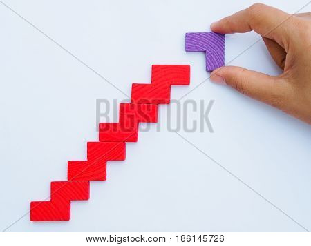Concept of building success foundation. Women hand put difference color of puzzle wooden blocks in the shape of a staircase