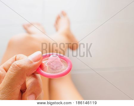 Hand holding condom and sexy legsselective focus save sex image.