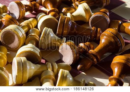 Black and white chess pieces fallen on chessboard