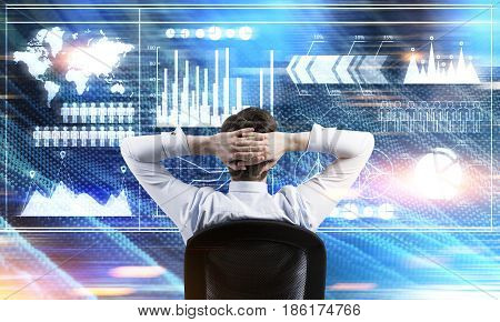 Rear view of a businessman sitting with his arms behind the head and looking at graphs. Toned image