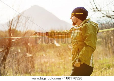 Portrait A man looks into the distance after striking slacklining equipment before performing crazy slacklining tricks and walking on slacklin in a park