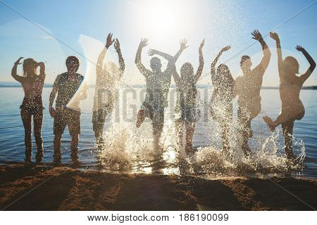 Cheerful young people splaching water while dancing on hot day
