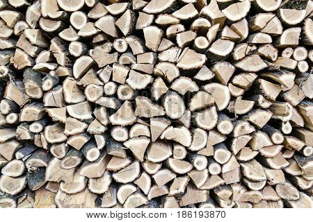Background of dry chopped oak firewood logs stacked up on top of each other in a pile. Background or a texture