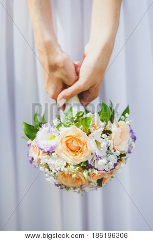 Bride in a white dress holding bouquet from spring flowers in hands on a white background close up. marriage, love, bride, wedding - concept. gatherings of bride.