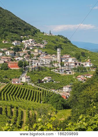 Small town of Valdobbiadene surrounded by vineyards zone of production of traditional italian white sparkling wine Prosecco. Vertical frame.
