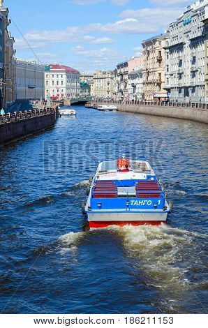 SAINT PETERSBURG RUSSIA - MAY 3 2017: Excursion ships on Moika River near Green Bridge in St. Petersburg. Unidentified tourists are visiting sights during walk along rivers and canals of city