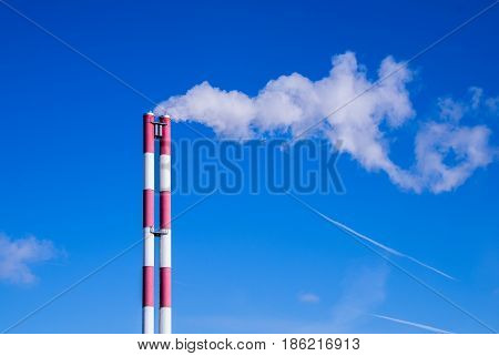 Two striped pipes smoke against a blue sky horizontal