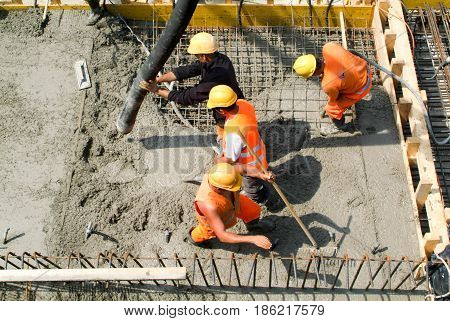 Street Workers Pouring Cement With A Pump Into A Highway Construction