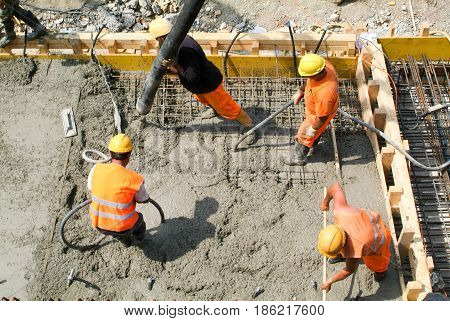 Street Workers Pouring Cement With A Pump Into A Highway Construction