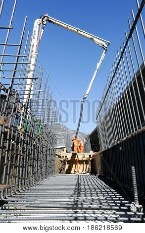 Street Workers Pouring Cement With A Pump Into A Highway Construction