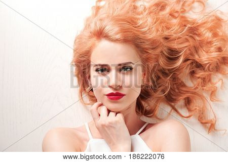 Young woman with strawberry blonde hair on wooden background