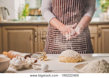 Woman slap his hands above dough closeup. Baker finishing his bakery, shake flour from his hands, free space for text. Homemade bakery, cooking process concept